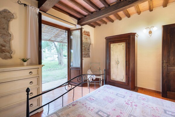 A bedroom with a bed, a dresser, a chair, and a wooden wardrobe.