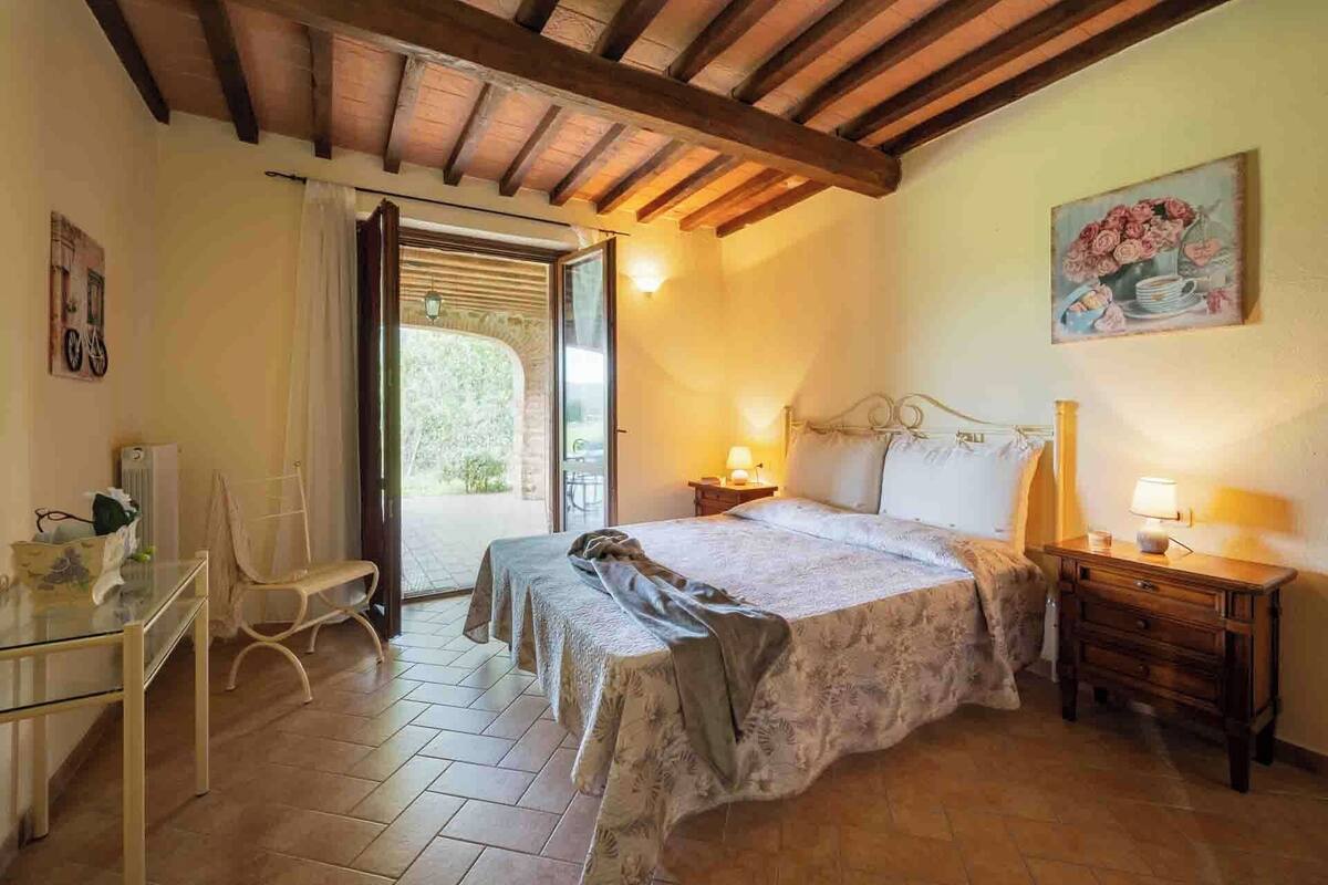 A bedroom with a bed, bedside tables, a chair, and a painting on the wall.