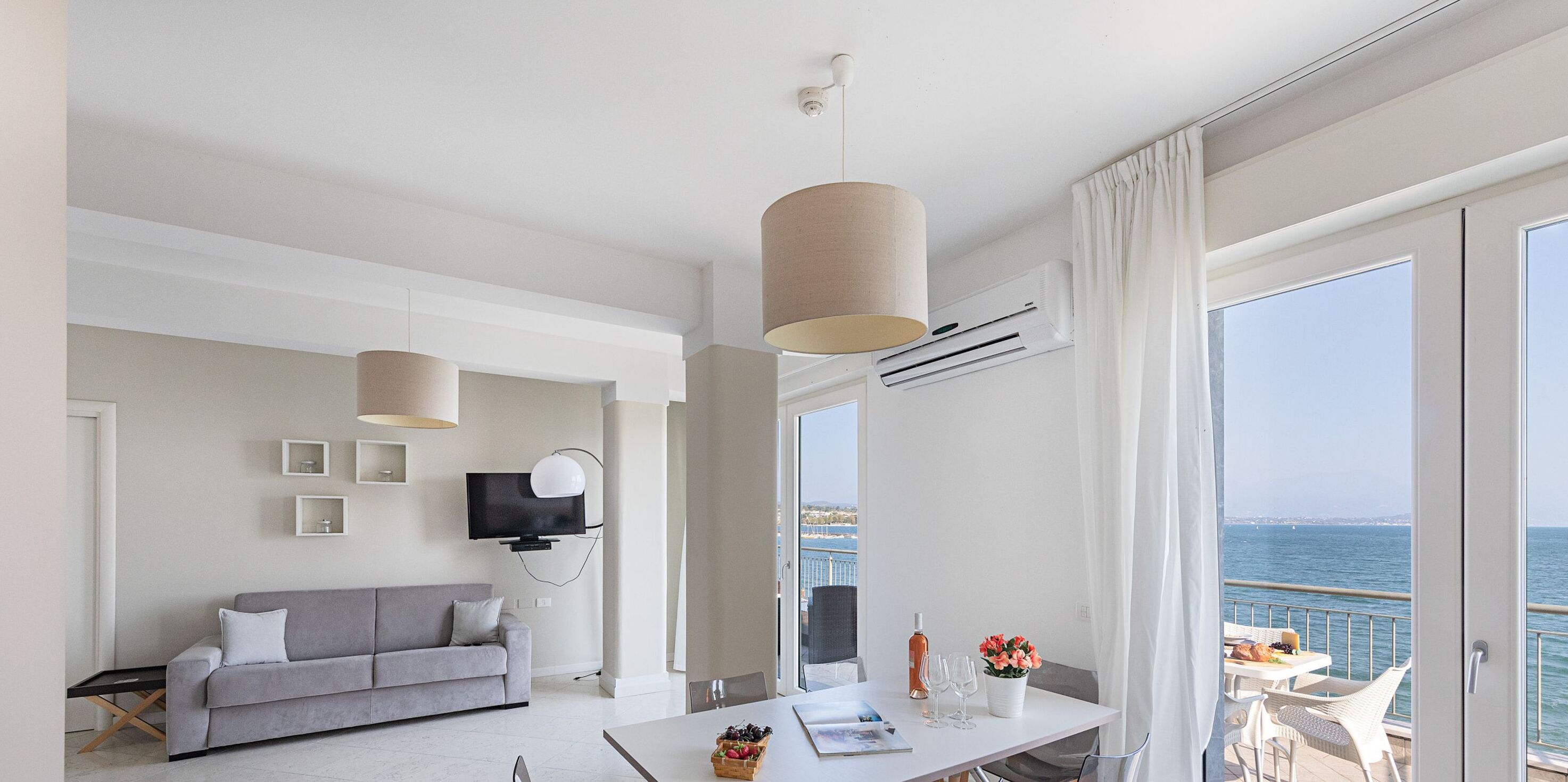 Habitación de hotel moderna con sofá, mesa de comedor y vista al mar.