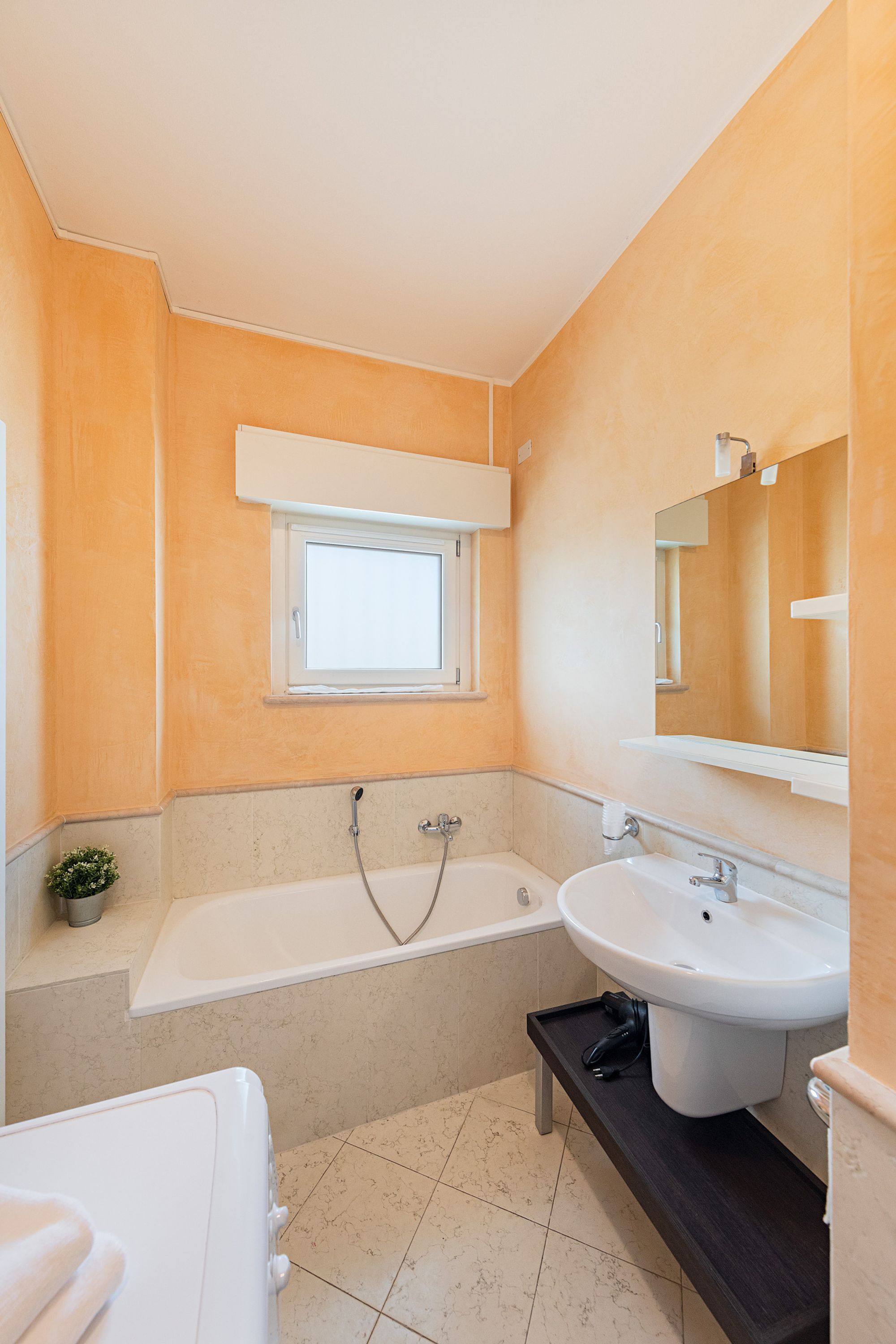 A bathroom with a bathtub, a sink, and a window.