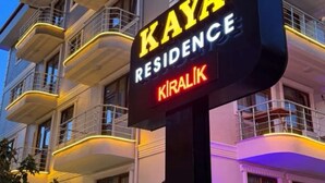 Un hotel a più piani con un cartello che riporta 'KAYA RESIDENCE KIRALIK' e una reception visibile.