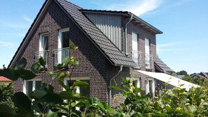 A two-story house with a steeply pitched roof, brick exterior, and white window frames. - Vacation apartment Birkenhof Alfsee  (Rieste)