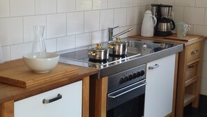 A compact kitchen with a stove, oven, and a coffee maker on the countertop. - Vacation apartment Birkenhof Alfsee  (Rieste)
