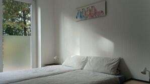 A bedroom with a bed, a nightstand, a lamp, and a wall-mounted zebra painting. - Vacation apartment Birkenhof Alfsee  (Rieste)