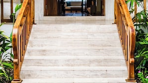 A grand staircase with marble steps and wooden railings leading to an arched doorway.