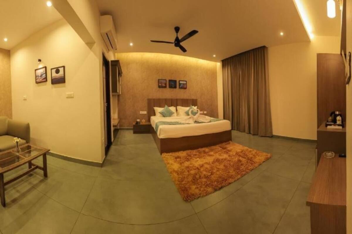 A modern hotel room with a bed, a sofa, a coffee table, and a ceiling fan.