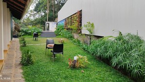A courtyard with a small seating area, a staircase leading to a door, and a wall with vertical gardens. - Holidays Garden Resort (Kalpetta)