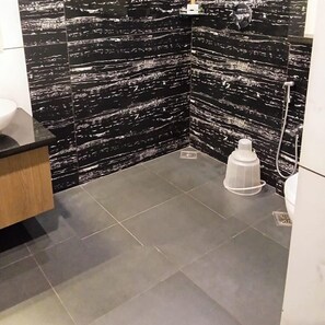 A bathroom with black marble walls, a white sink, and a shower area. - Holidays Garden Resort (Kalpetta)