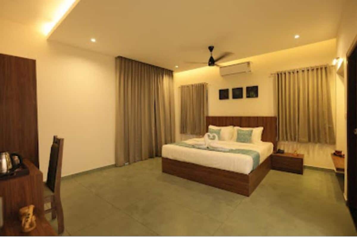 A hotel room with a large bed, a ceiling fan, and a small bedside table.