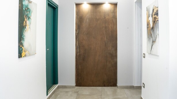 A hallway with a brown elevator door, a green door, and two abstract paintings on the walls. - Duomo 5 - Maria s Bright Flat at the Cathed w Balc (Naples)