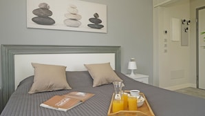 A neatly made bed with a tray of breakfast items, a bedside lamp, and a painting of stacked stones on the wall. - Villa Caterina 10 - LOC (Desenzano del Garda)