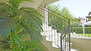 A staircase with metal railings, a potted plant, and a view of a residential area with houses and greenery. - Villa Caterina 10 - LOC (Desenzano del Garda)