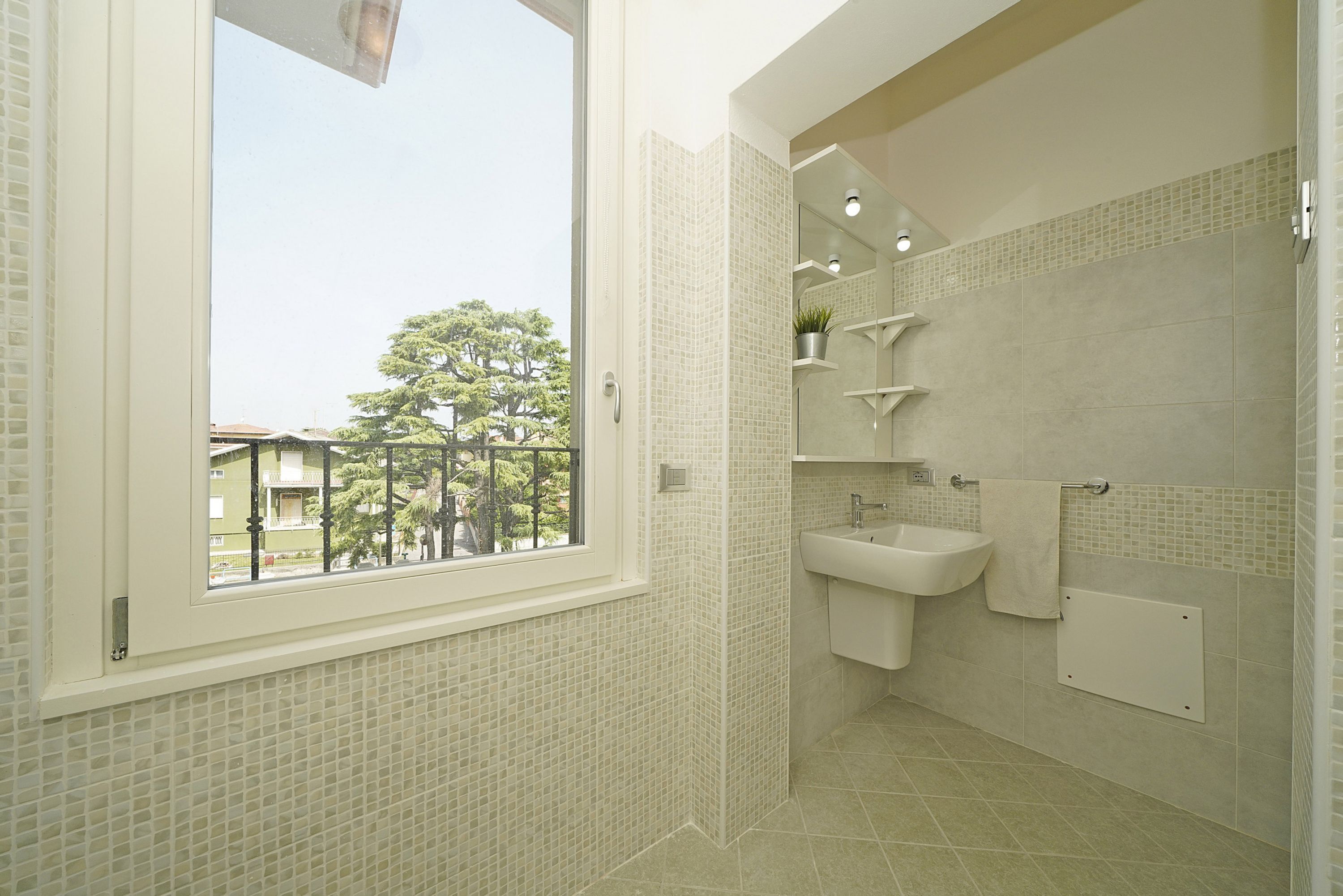 Baño con ventana, lavamanos y zona de ducha.