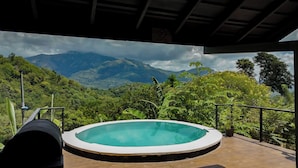 A hot tub on a wooden deck with a view of a mountainous landscape.