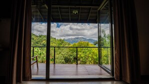 A room with a large sliding glass door leading to a balcony with a view of a mountainous landscape.