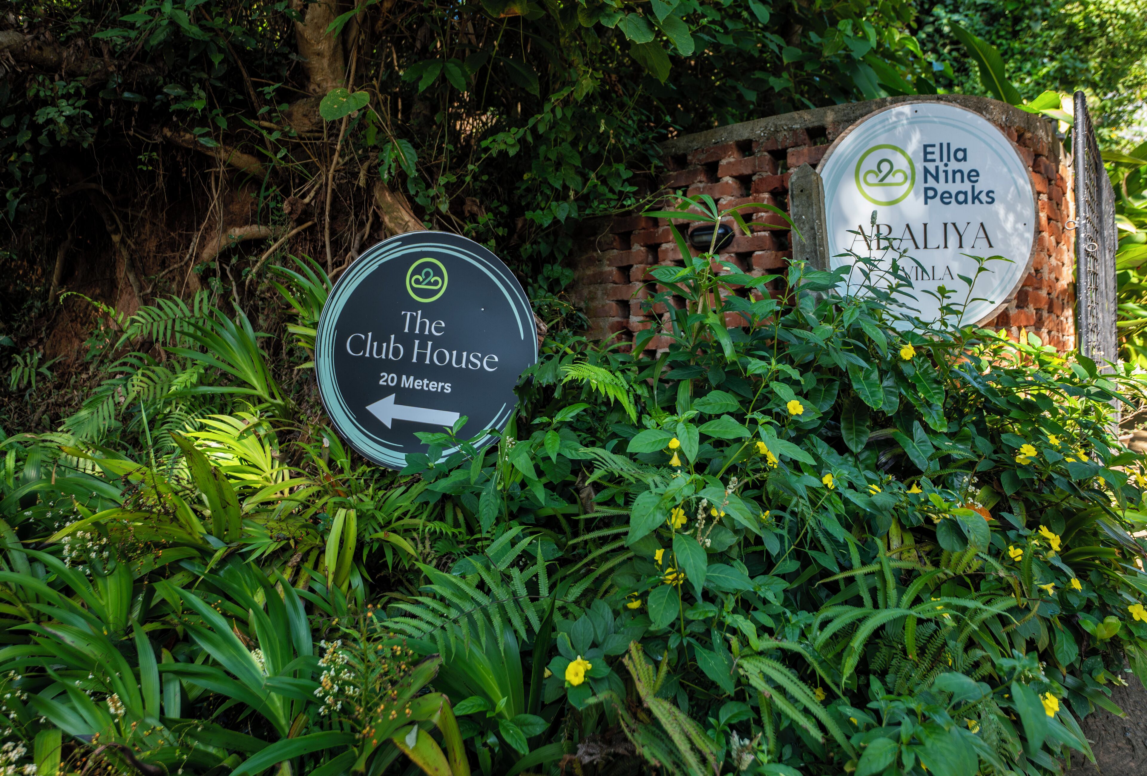 Two signs, one for 'The Club House' and another for 'Ella Nine Peaks Bali'.