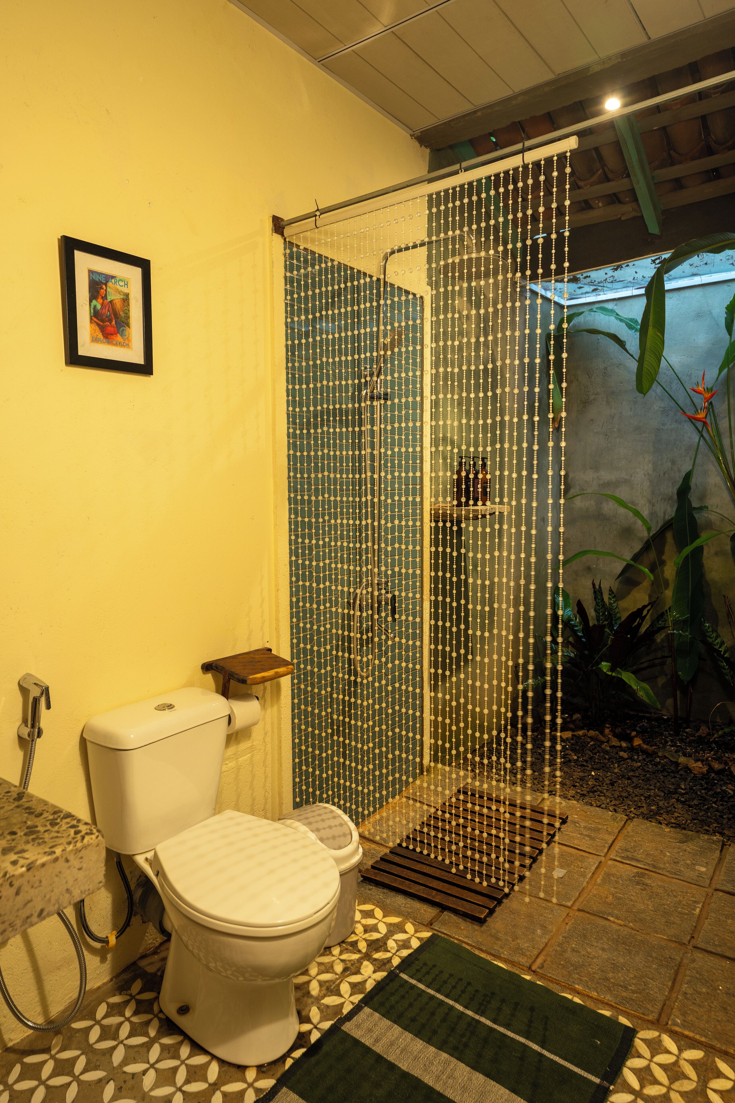 A bathroom with a toilet, shower enclosure, and a small shelf.