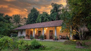 A house with a tiled roof, a porch with chairs, and a garden.