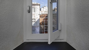 A room with a white door and window, a black floor, and a view of historic buildings. - Raibetta Apartments - Two (Genoa)