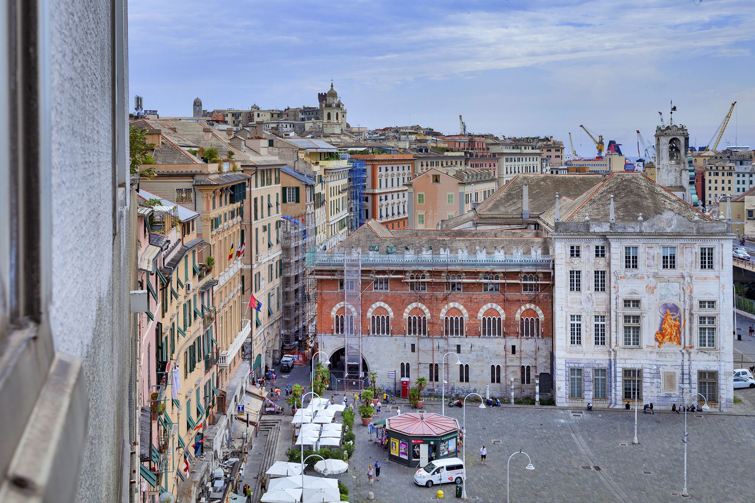 Un edificio histórico con un patio central, rodeado de edificios de varios pisos con balcones y una mezcla de estilos arquitectónicos.
