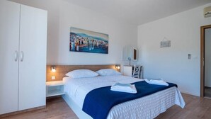 A bedroom with a large bed, a wardrobe, a painting on the wall, and a bedside table. - Apartments Njirić - Standard Studio with Balcony and Sea View - No.1 (Zaton)