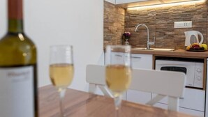 A modern kitchen with a stone backsplash, white cabinetry, and a dishwasher. - Apartments Njirić - Standard Studio with Balcony and Sea View - No.1 (Zaton)