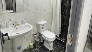 Habitación triple familiar, vistas al patio | Baño | Ducha, artículos de higiene personal gratuitos, toallas y jabón