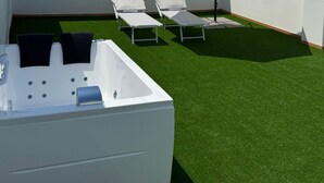 A rooftop terrace with artificial green turf, two white lounge chairs, a white umbrella, and a white hot tub. - Samarè Rooms & Apartments (Bisceglie)