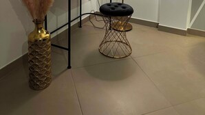 A modern room with a black vanity, a gold vase with pampas grass, a round stool, and a floor lamp. - Samarè Rooms & Apartments (Bisceglie)