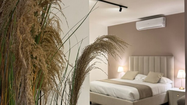 A bedroom with a bed, bedside tables, and a modern air conditioning unit. - Samarè Rooms & Apartments (Bisceglie)