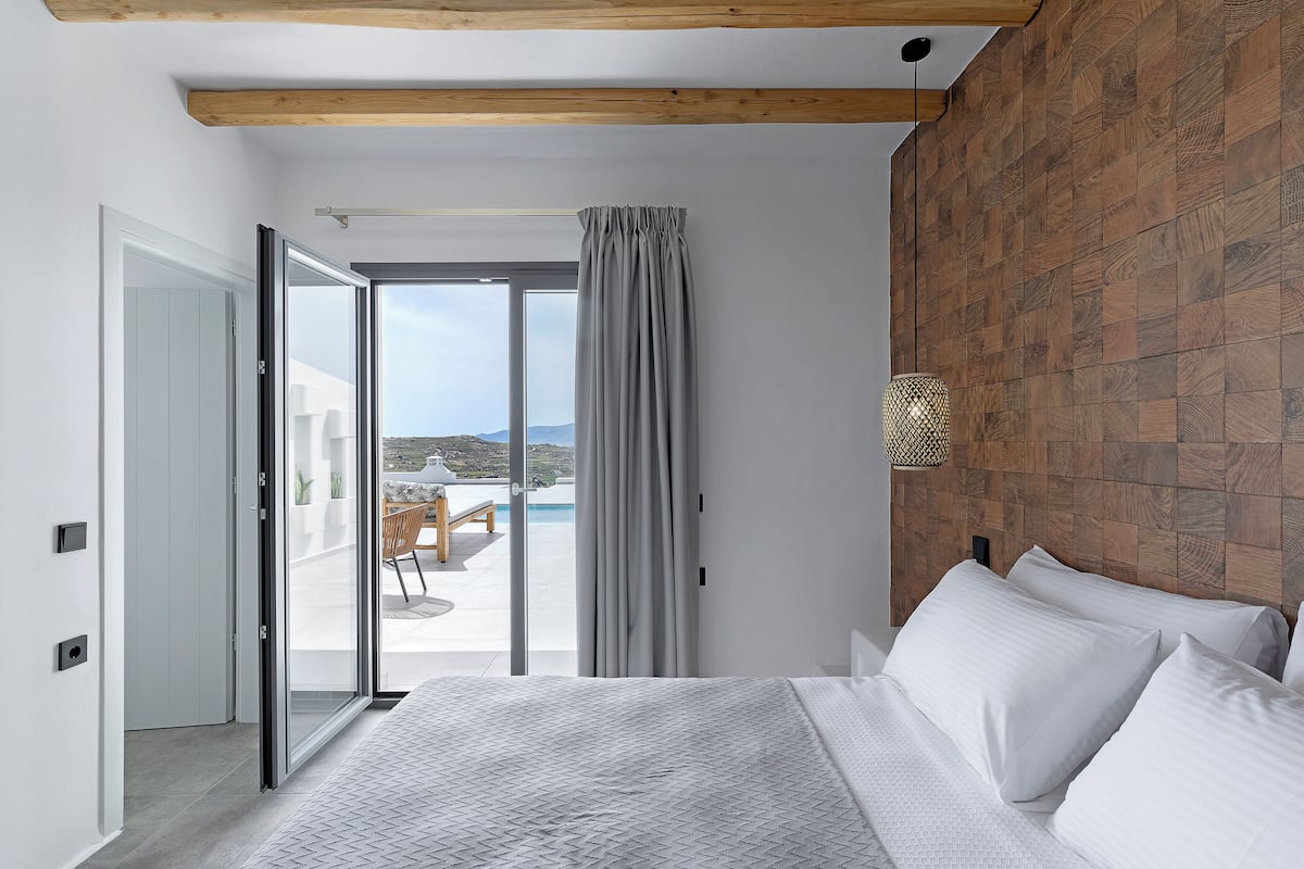 Een slaapkamer met een bed, een schuifdeur naar een balkon en een houten wand.