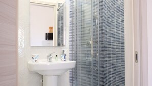 A bathroom with a white sink, mirror, and glass shower enclosure.