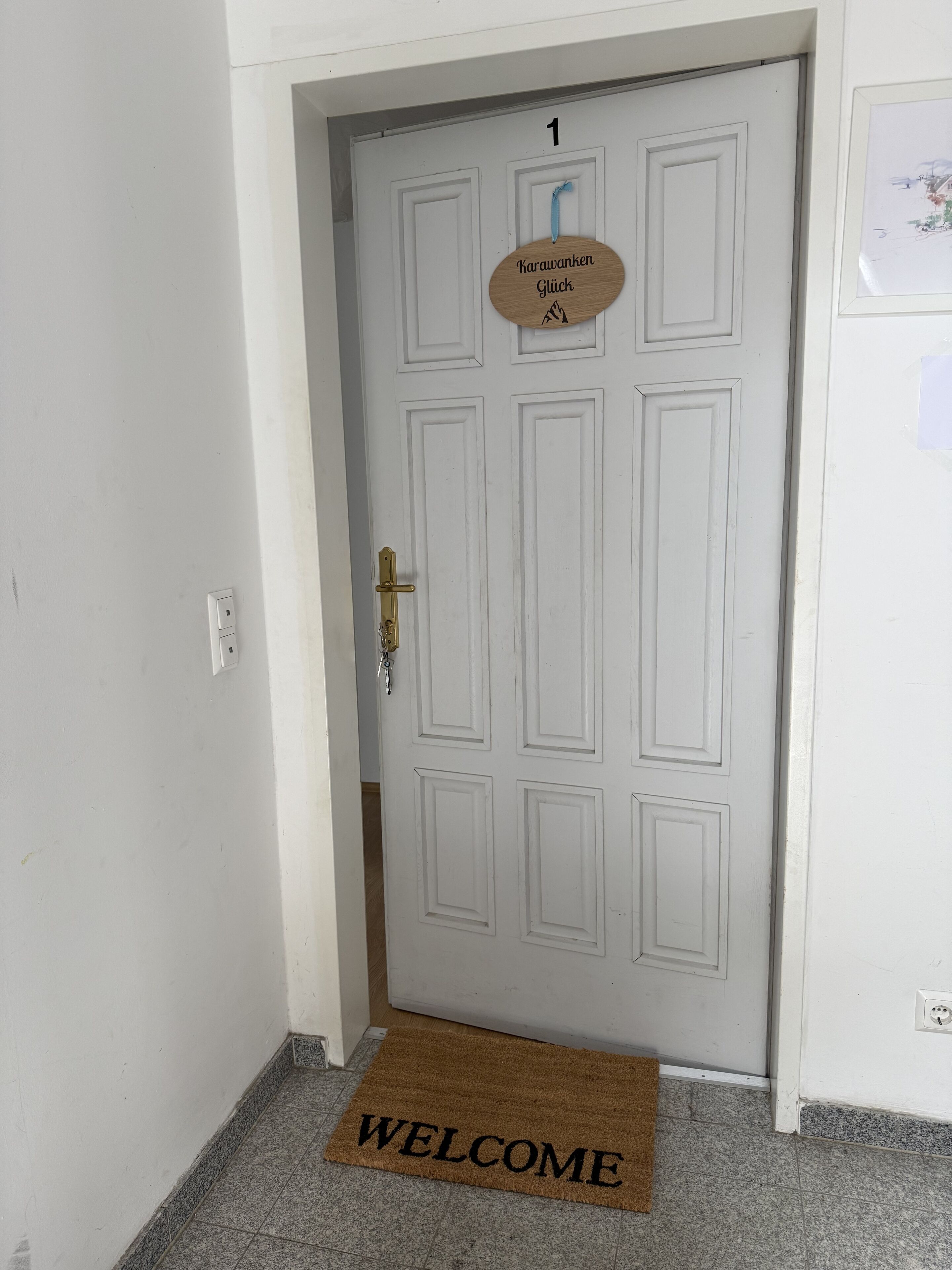 A white door with a "WELCOME" mat and a sign above it.