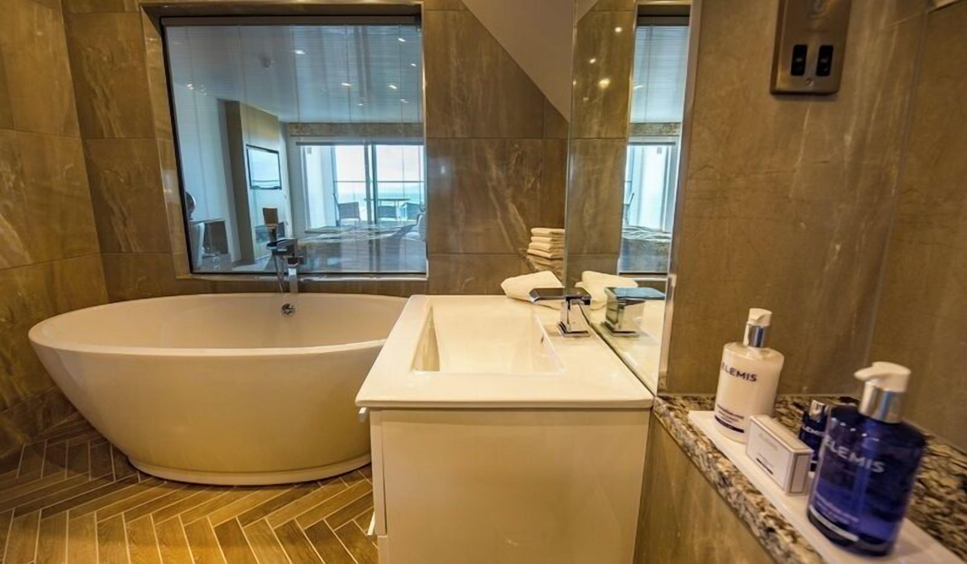 A modern bathroom with a freestanding bathtub, a vanity with a mirror, and toiletries.