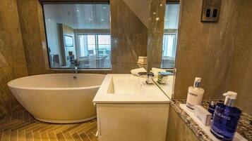 A modern bathroom with a freestanding bathtub, a vanity with a mirror, and toiletries.