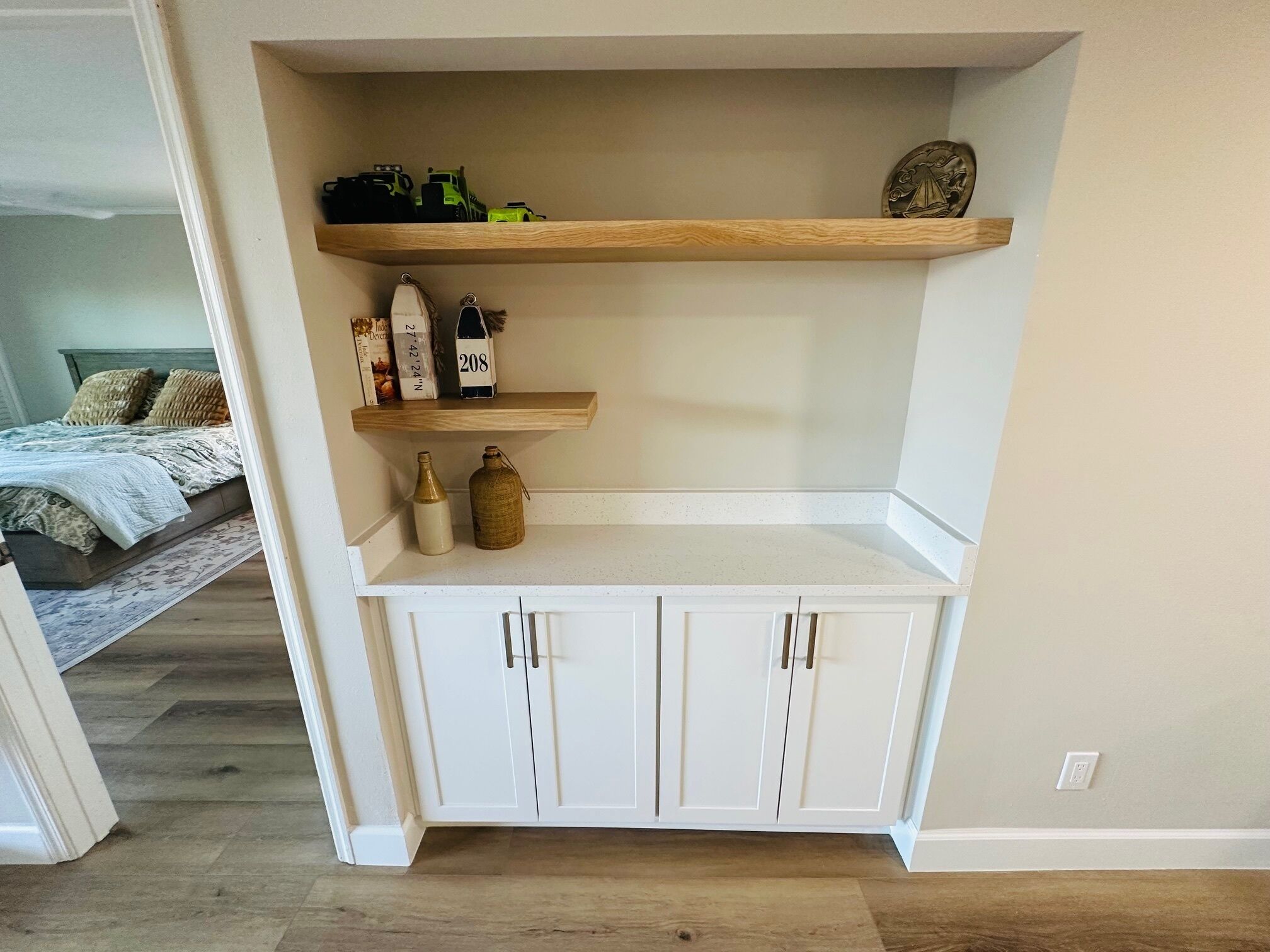 Un dormitorio con una cama, una mesita de noche y una estantería con objetos decorativos.
