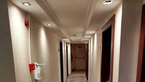 A hotel hallway with a checkered floor, recessed lighting, and doors on both sides. - Martin City Hotel (Bursa)