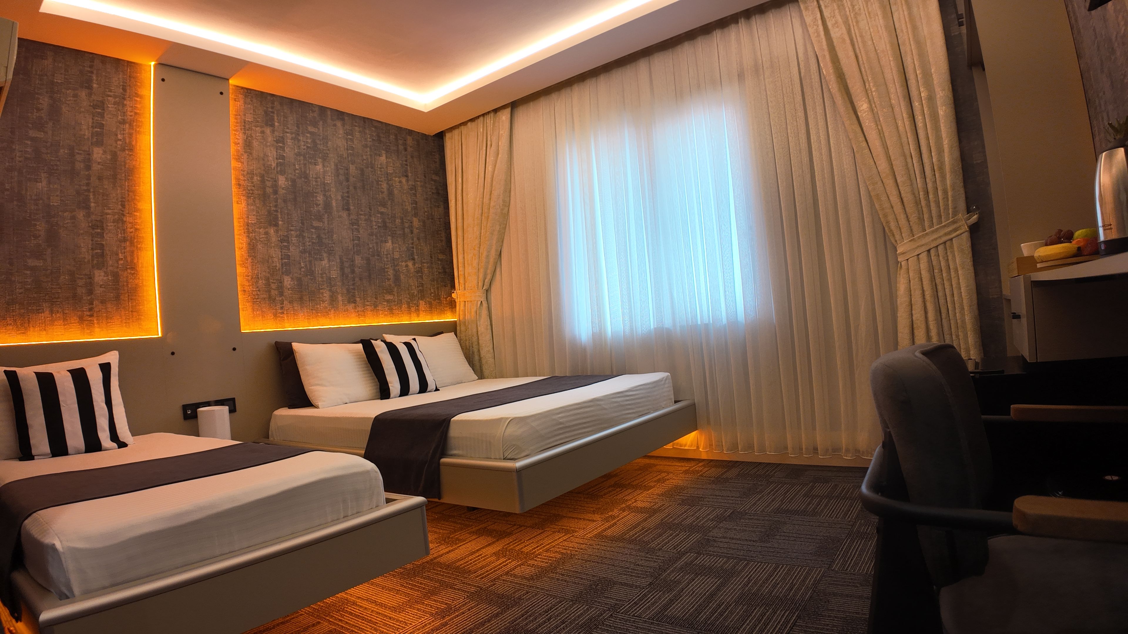 A hotel room with two beds, a desk, and a chair.