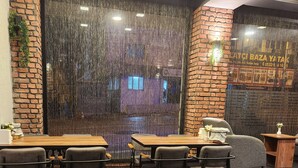 A restaurant with a brick wall, wooden tables, and chairs. - Martin City Hotel (Bursa)