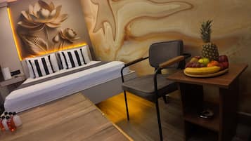Une chambre à coucher moderne avec un lit, une chaise, une table avec des fruits et un mur orné d’un motif floral.