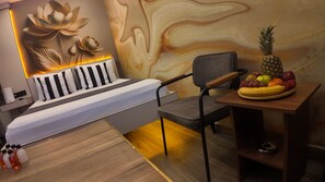 Un dormitorio moderno con una cama, una silla, una mesa con fruta y una pared decorada con un diseño floral.