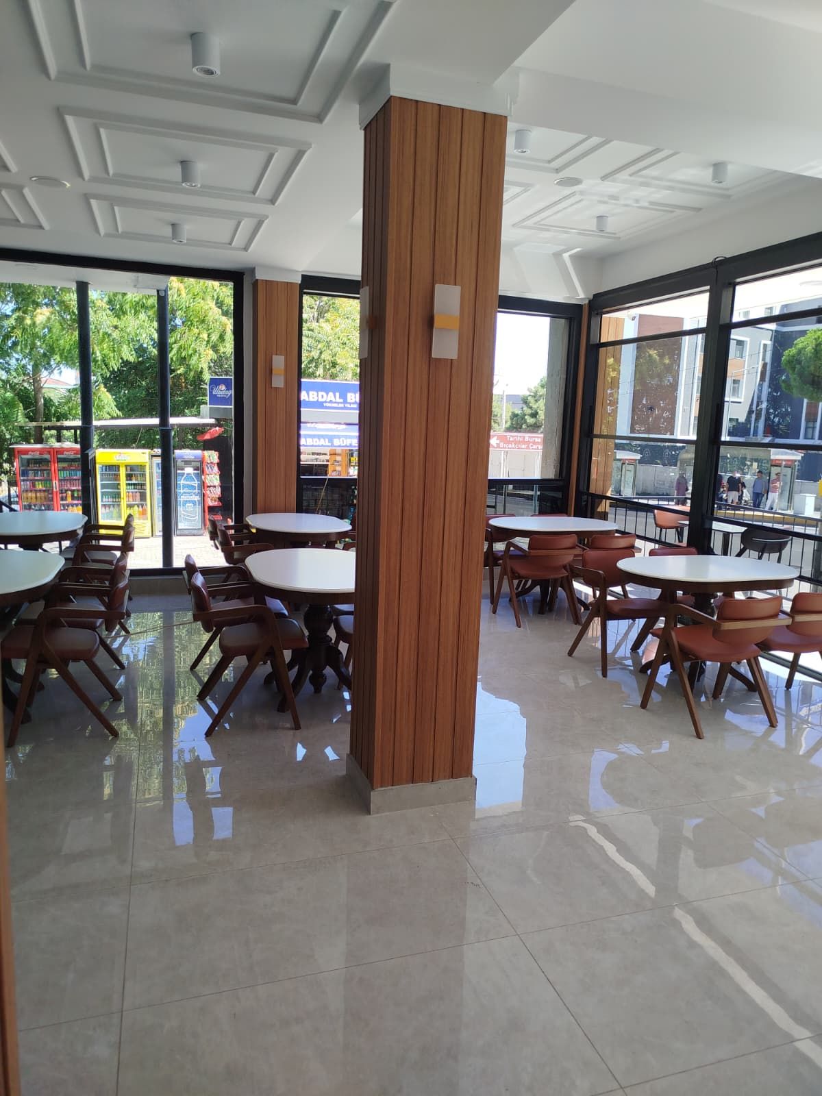 Un espace de restauration intérieur moderne, avec des piliers en bois, des tables rondes et des chaises.