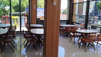 Un espace de restauration intérieur moderne, avec des piliers en bois, des tables rondes et des chaises.
