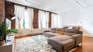 A modern living room with a sofa, glass coffee table, and a brick wall. - Adorable Loft in the Old Montreal  (Montreal)