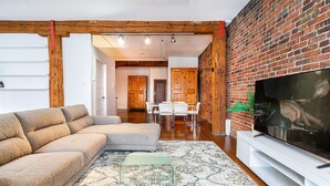 A living room with a sectional sofa, a glass coffee table, a flat-screen TV, and a patterned rug. - Adorable Loft in the Old Montreal  (Montreal)