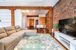 Relax in this stylish living room with a large sectional sofa, flat-screen TV, and dining area.