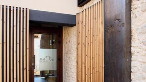 Una entrada moderna con una puerta de listones de madera y una pared de piedra.
