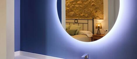 A bathroom with a round mirror, white sink, and a textured wall behind the mirror.