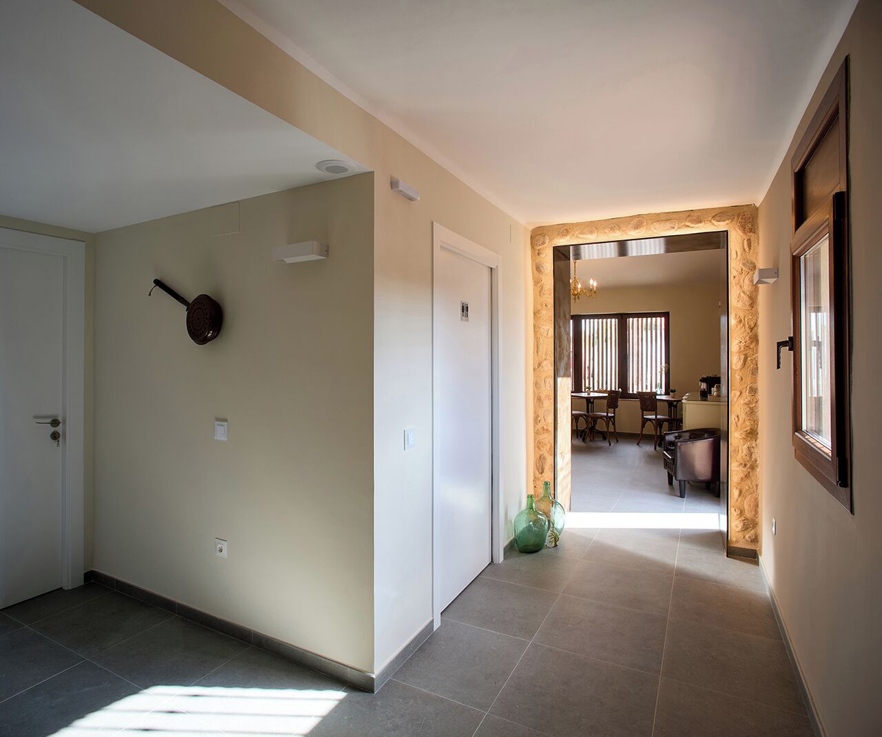 Un pasillo que conduce a un comedor con una mesa y sillas, una guitarra en la pared y una puerta a la izquierda.
