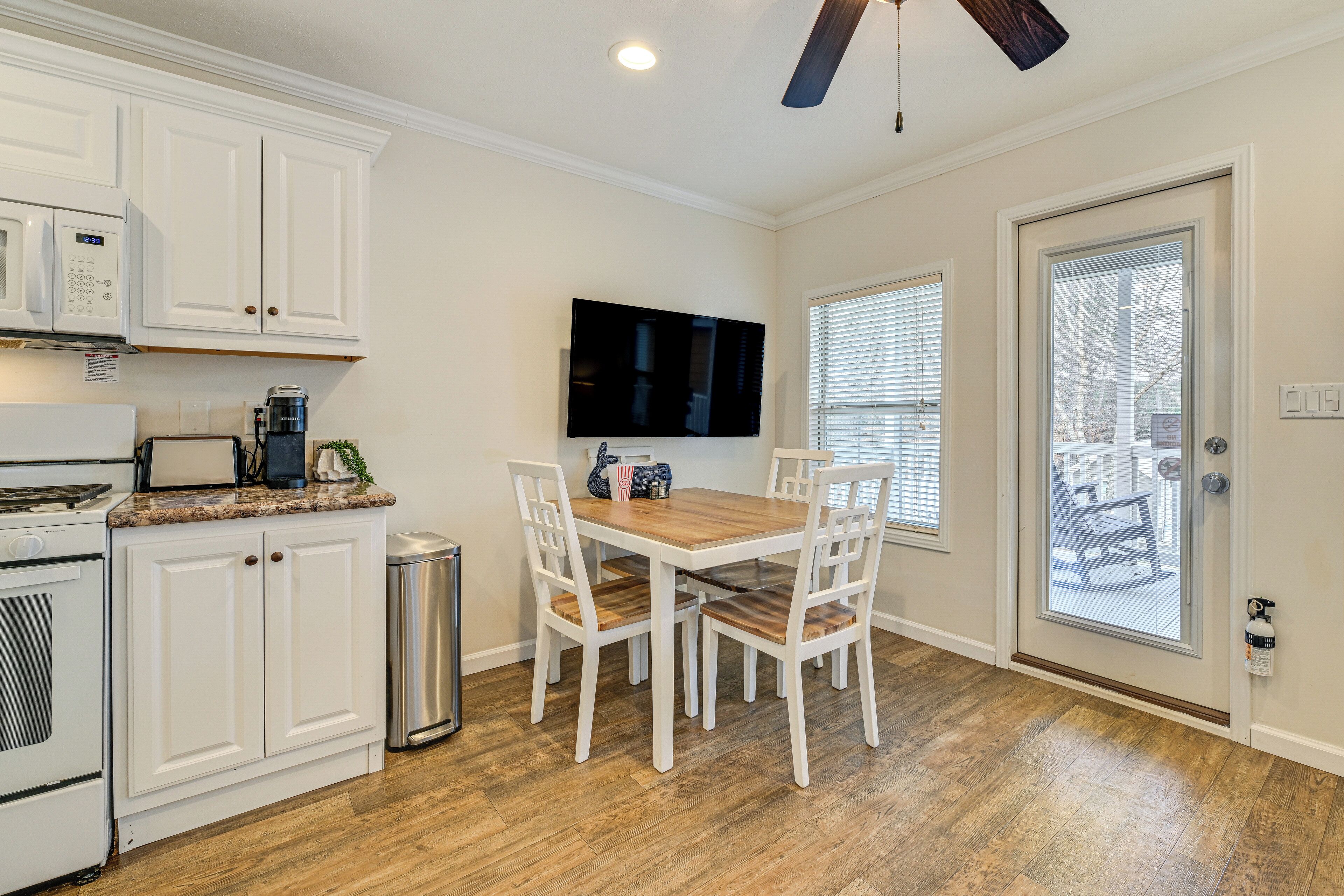 A kitchen with white cabinets, a microwave, a stove, and a dining table with four chairs.
